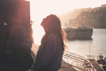 woman tilts her head back and closes her eyes at sunset