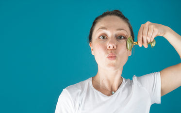 woman uses a jade face roller on her cheekbones