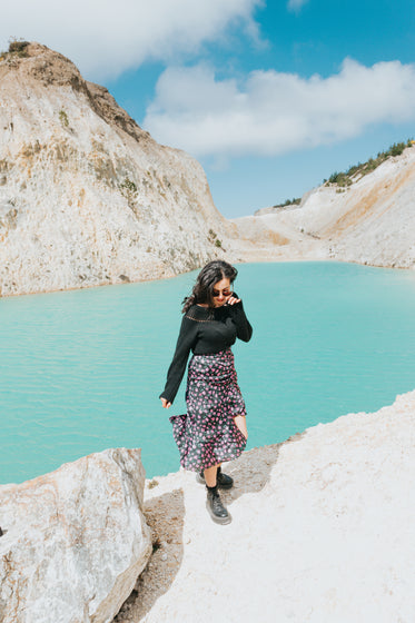 woman walk towards the camera by a blue lake