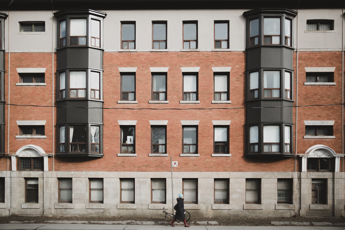 A woman walking past a city apartment building at dusk