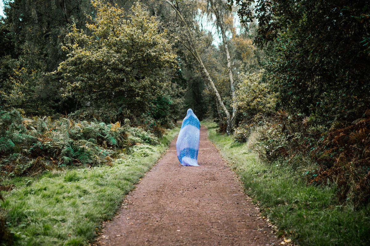 Mulher caminha pela trilha com cabeça coberta
