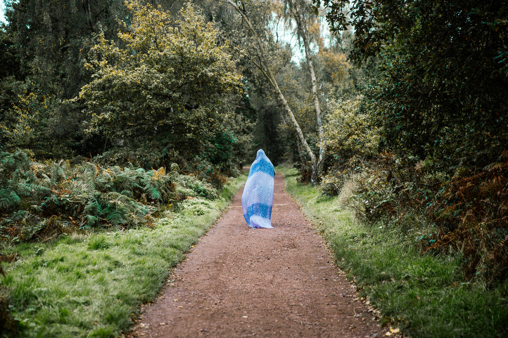 mulher caminha pela trilha com a cabeça coberta