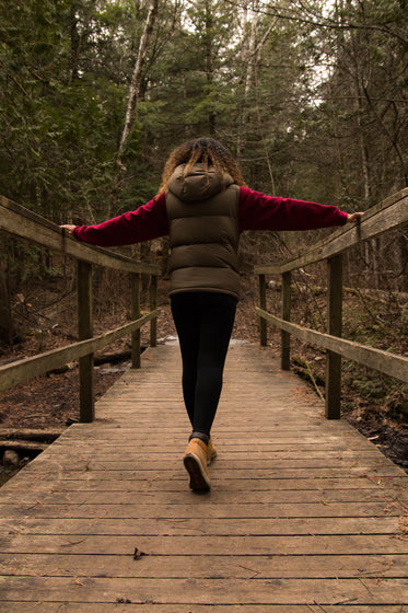 woman walks across bridge in forest
