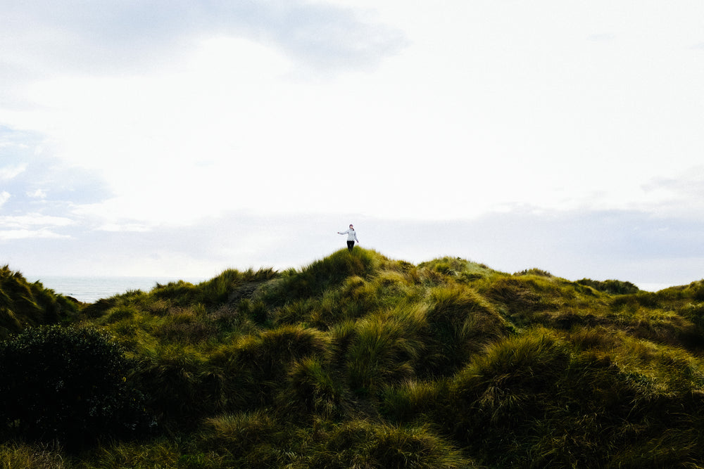 woman walks across grassy dunes