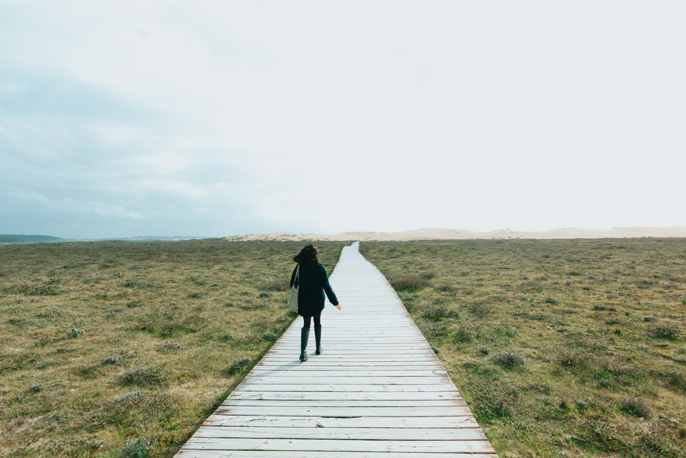 woman walks down a flat wooden boardwalk