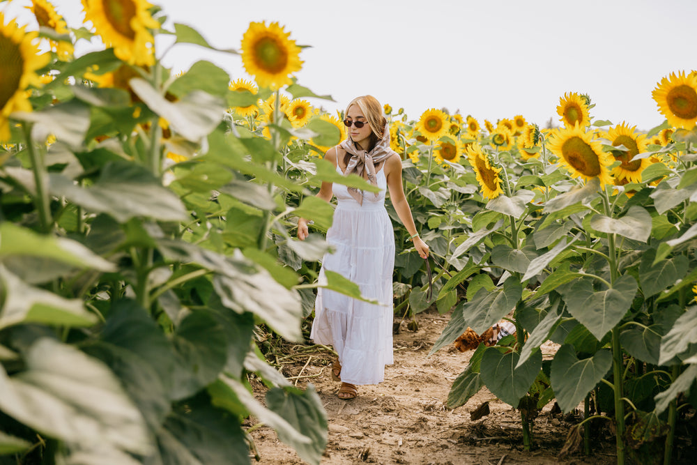 woman walks through a field of sunflowers