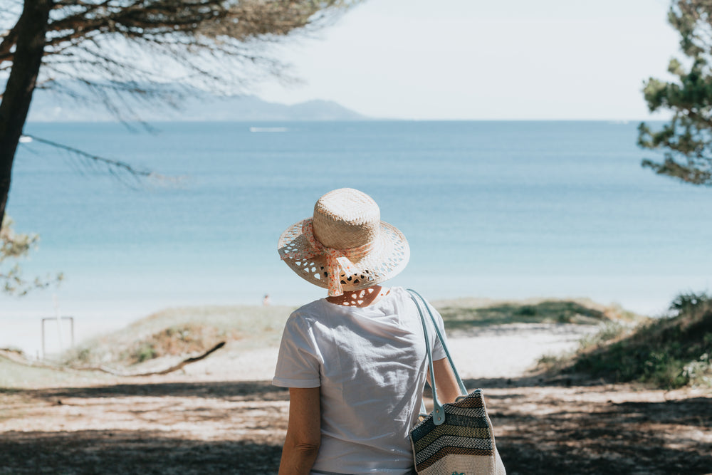 woman walks towards a beach and blue water