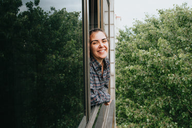 woman with a wide smile leaning out a window