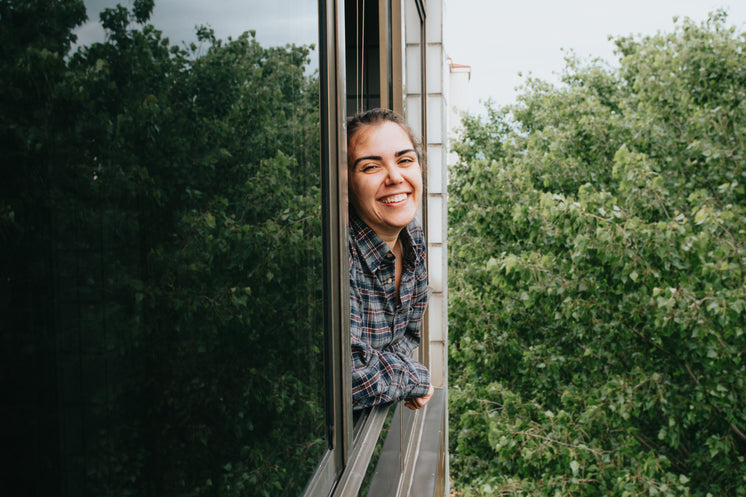 Woman With A Wide Smile Leaning Out A Window