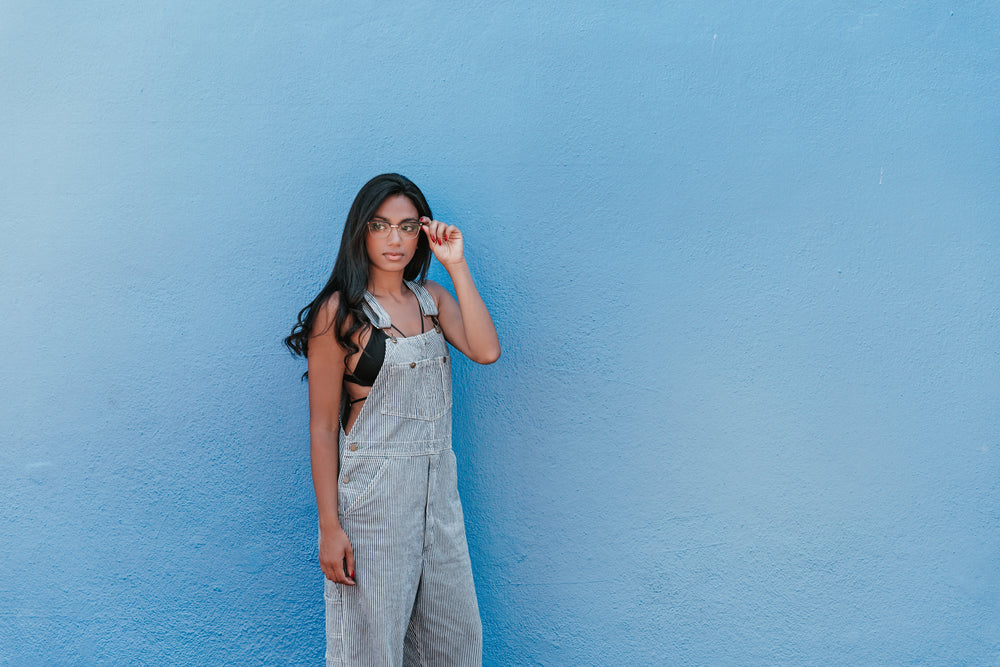 woman with blue wall adjusts glasses