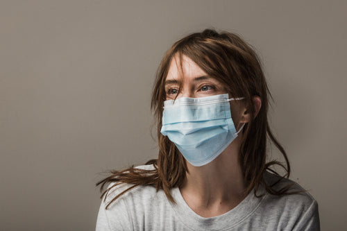 woman with brown hair wearing disposable face mask