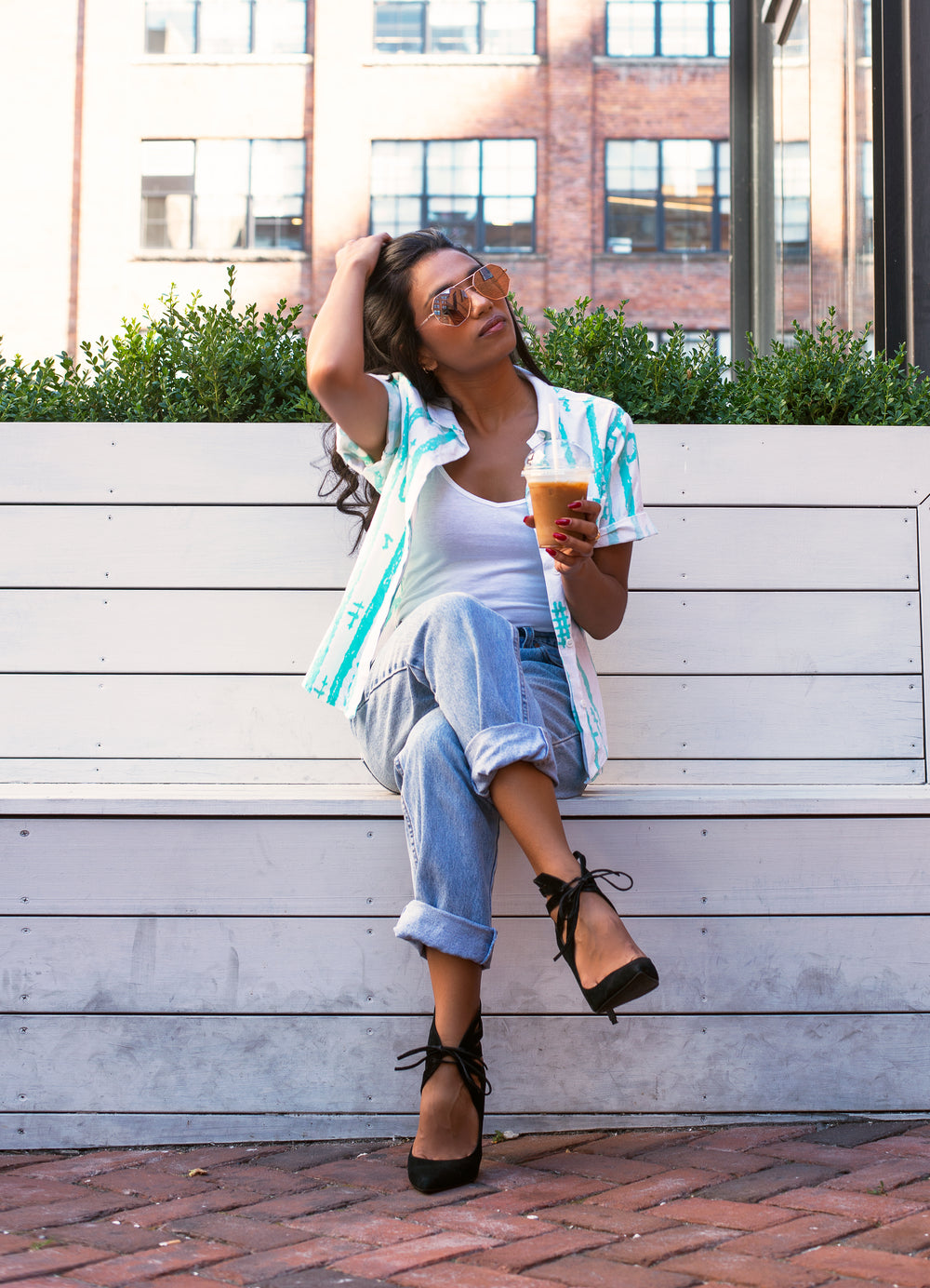 woman with coffee runs hands through hair