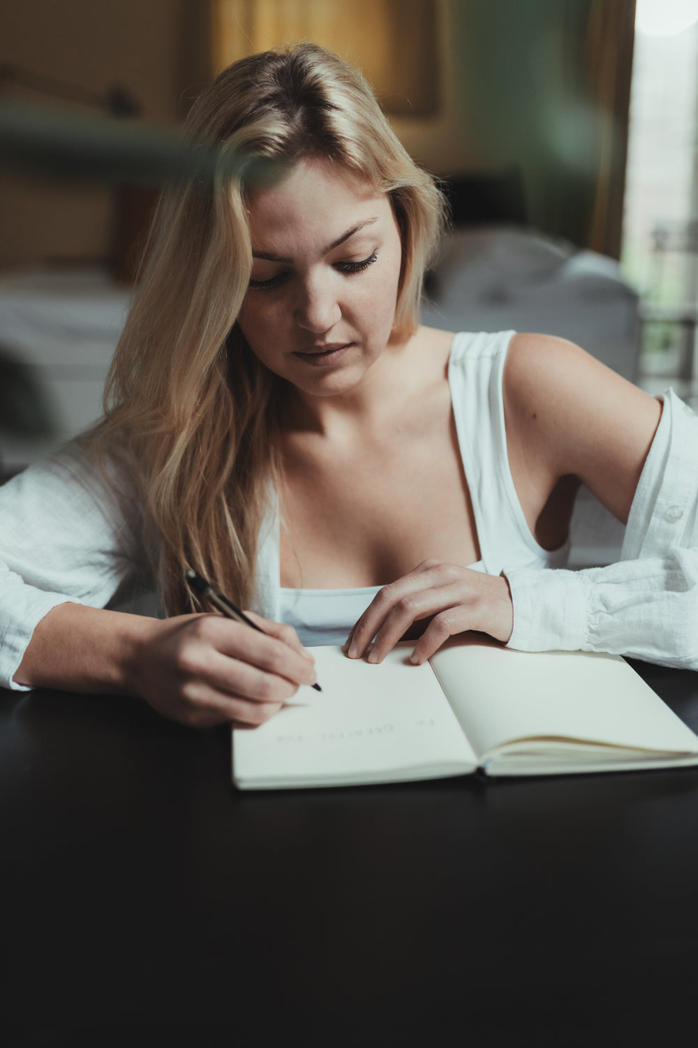 woman writes in a open notebook in her lounge