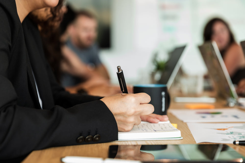 woman writing in notebook during meeting