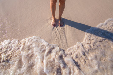 womans feet in sand with waves