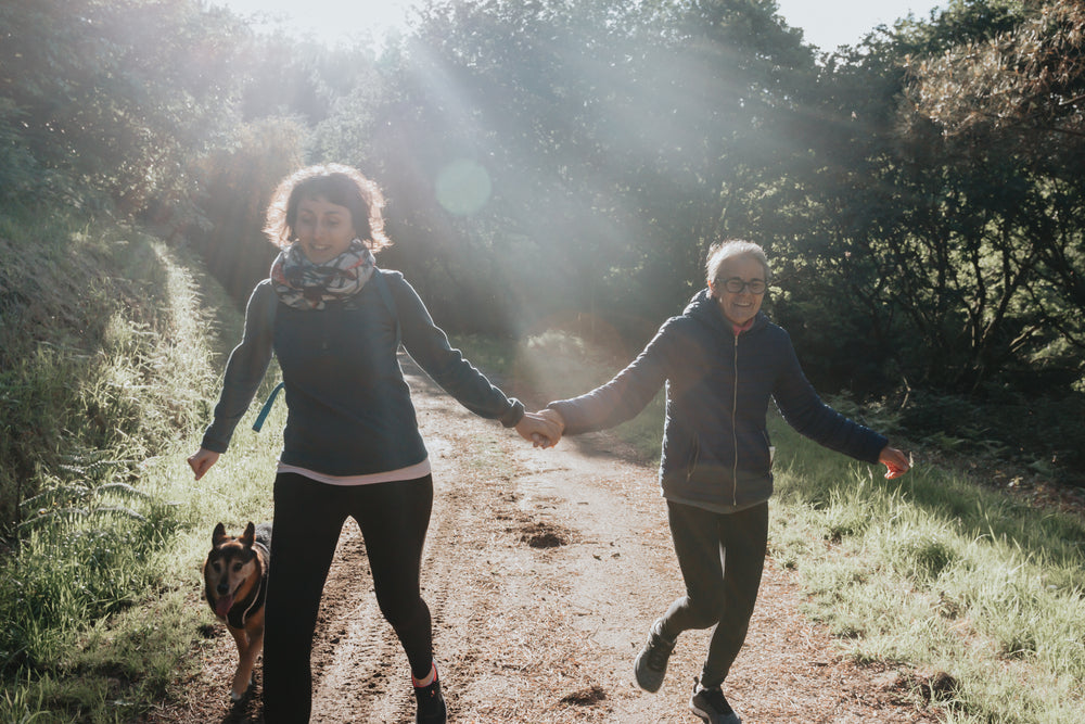 women hold hands as they walk down a path