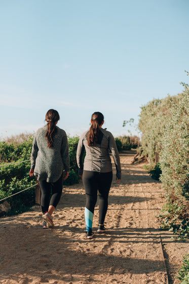 women in activewear hike up sandy california coastline path