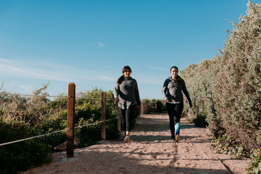 women in activewear take a beachside hike on a sandy path