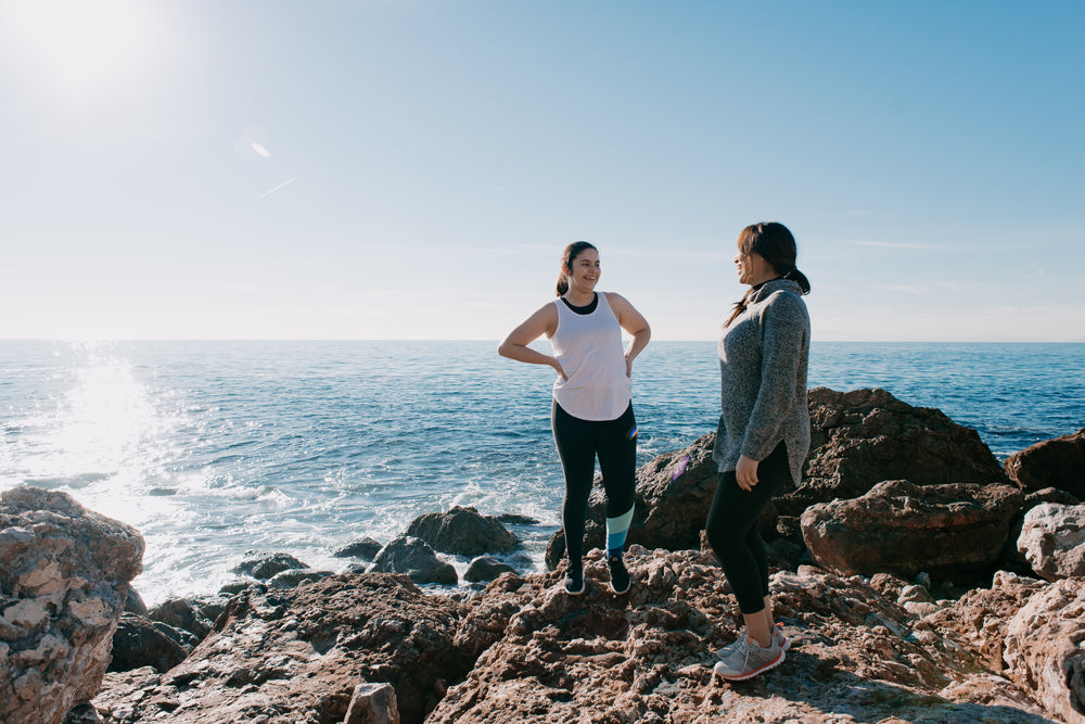 women in activewear take a moment to share a laugh on beach