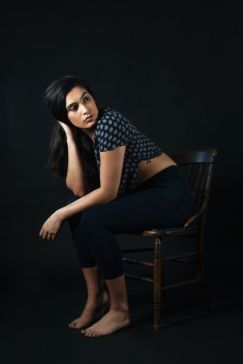 women looks away while sitting on wooden chair