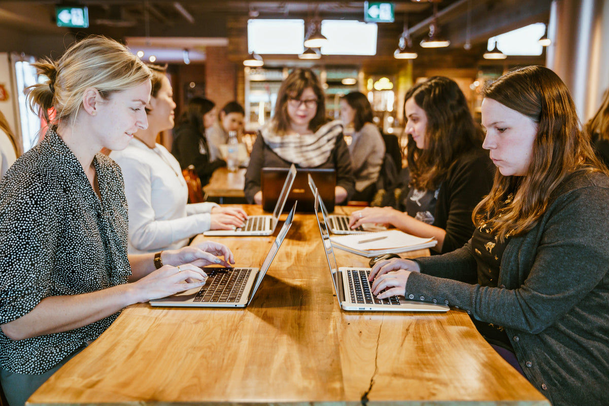 女人们围着桌子坐在笔记本电脑上