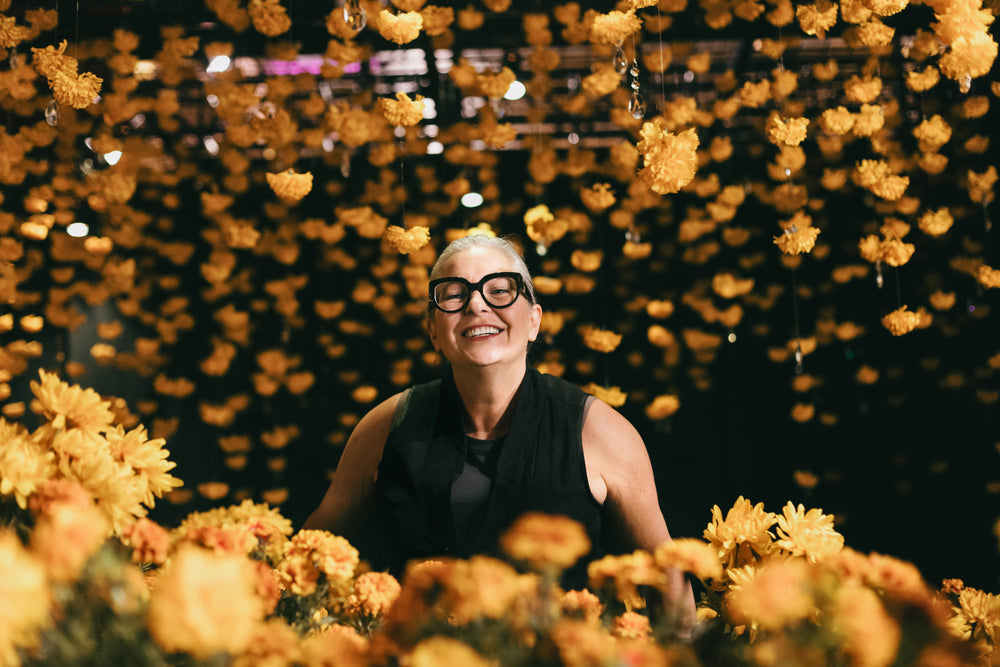 women peeking over yellow flowers
