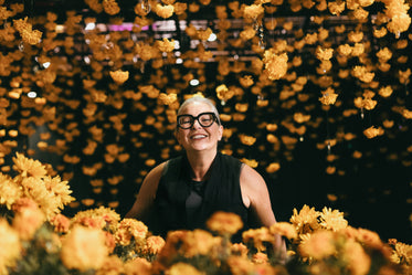 women peeking over yellow flowers