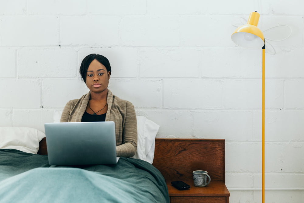 women sits in bed with laptop and coffee