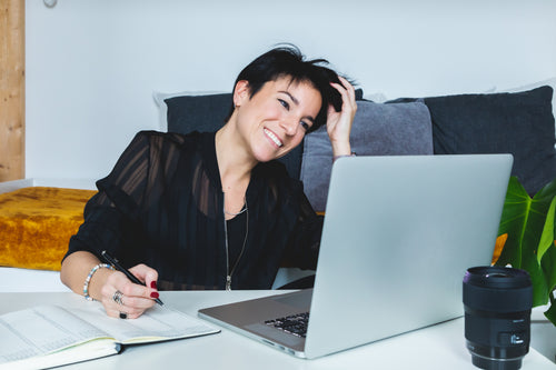 women smiles as she works from home on her laptop
