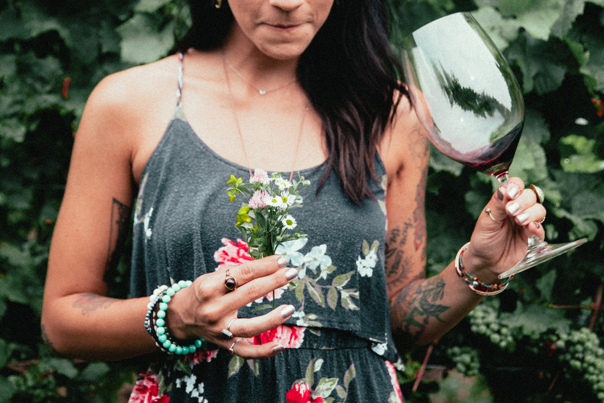 mulher tatuada e estilosa segurando flores e taça de vinho