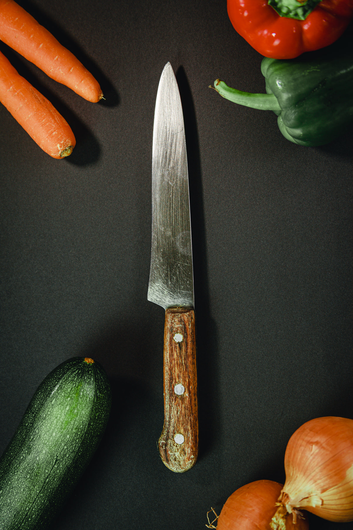 wood handled knife surrounded by vegetables