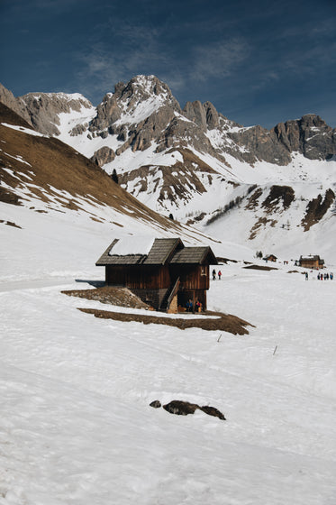 wooden cabin below snowcapped mountains