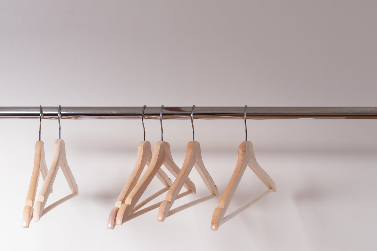 wooden clothes hangers cling emptily to the shiny shop rack