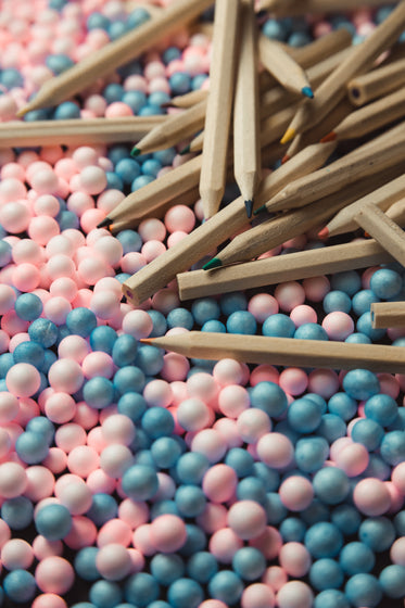 wooden colored pencils scattered on pink and blue balls