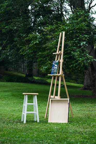 wooden easel stands outside with a wood stool