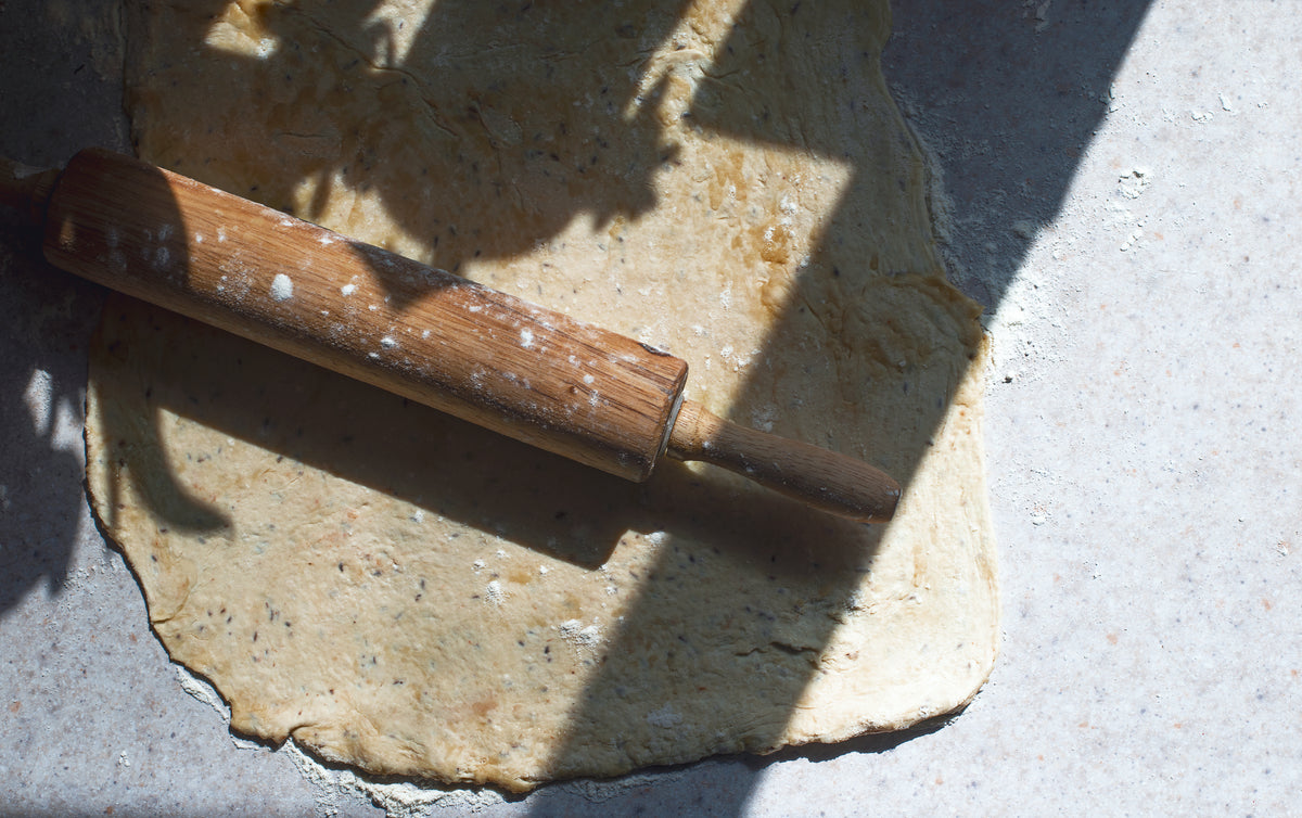 wooden rolling pin lays on top of rolled out dough