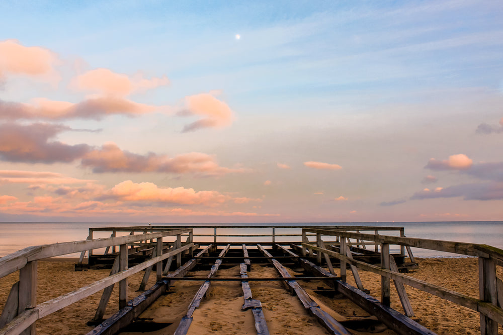 wooden structure reaching to water at sunset