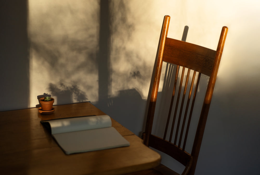 wooden table and chair with a notebook and small plant