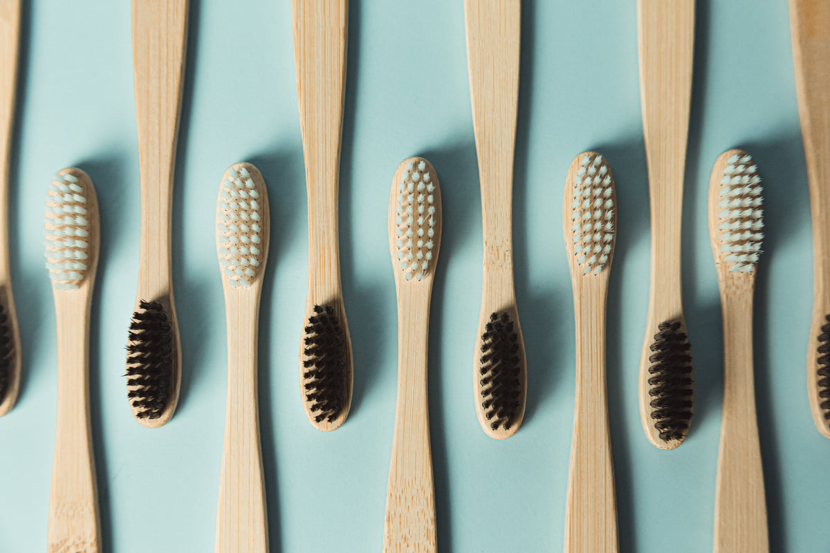 wooden toothbrushes in a row against a green background