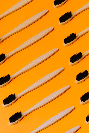 wooden toothbrushes lay on a vibrant orange background