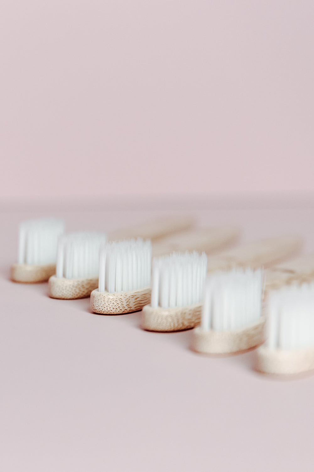 wooden toothbrushes lined on bright pink background