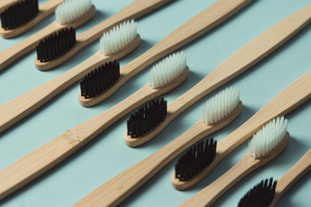  wooden toothbrushes lined up against a green background