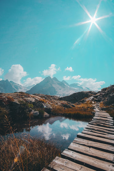 wooden walkway over water into rocky mountain pathway