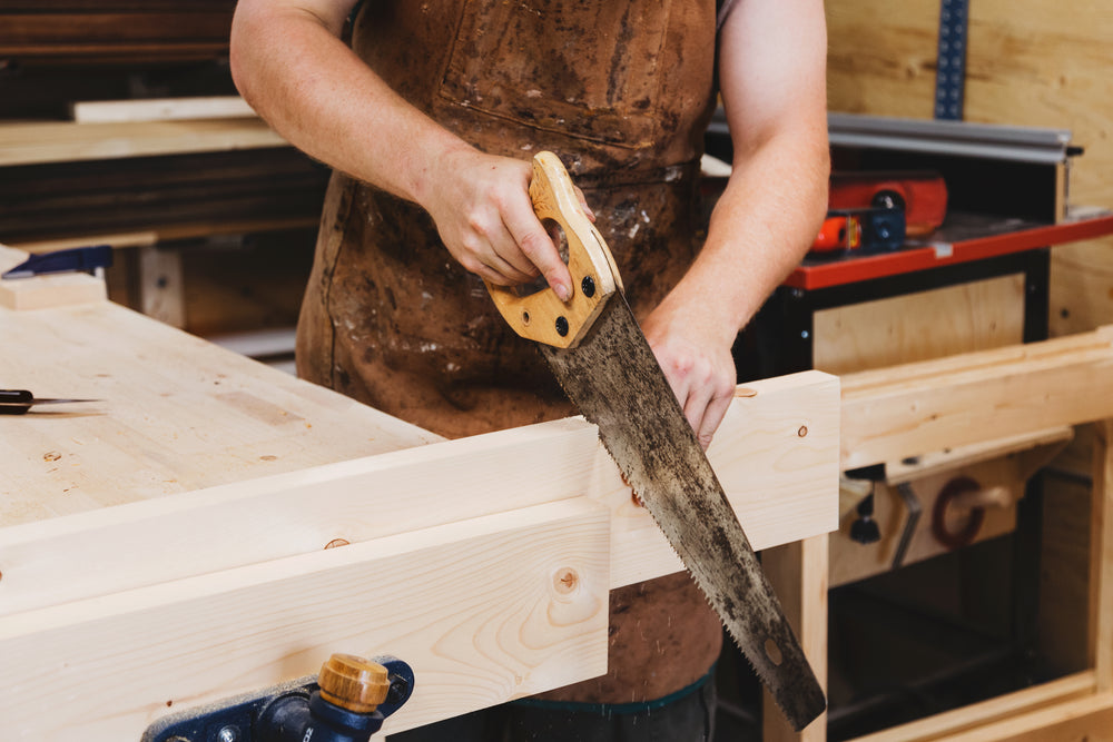 woodworker using handsaw in workshop