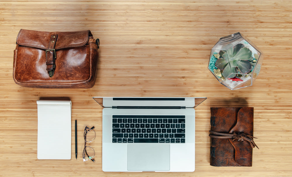 workspace flatlay with leather bag and notebook