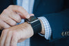 wrists of a person in a blue suit with a smart watch