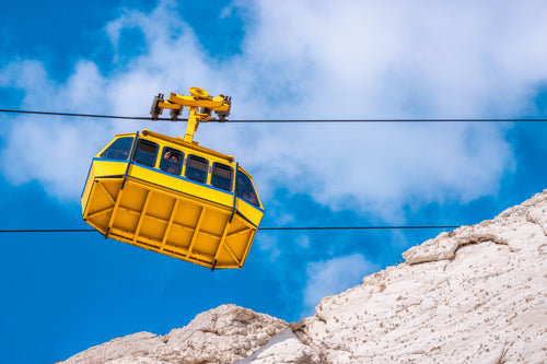 yellow cable car and white rocky mountains