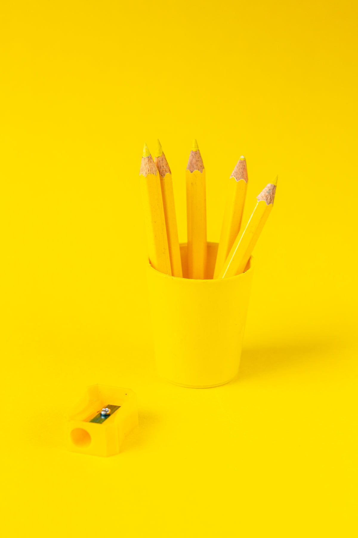黄色的铅笔杯和尖锐在黄色的背景