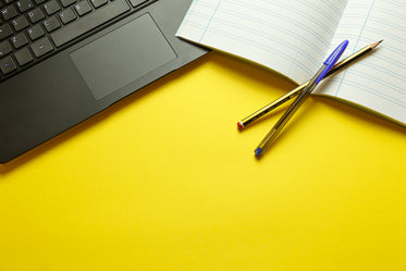 yellow table with lined notebook and computer