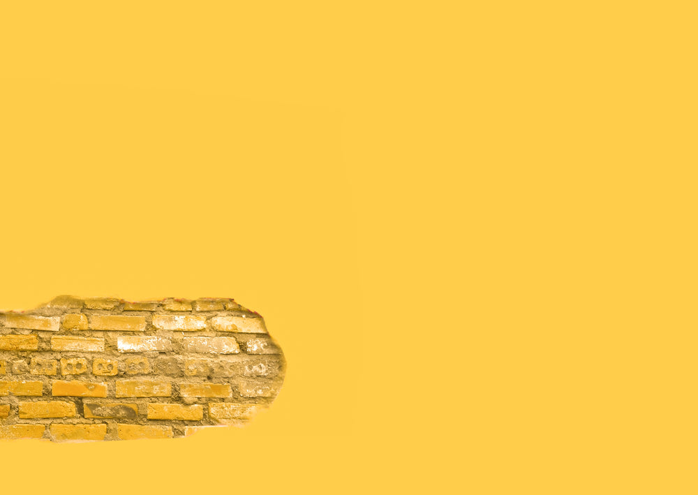 yellow wall with a section of exposed brick